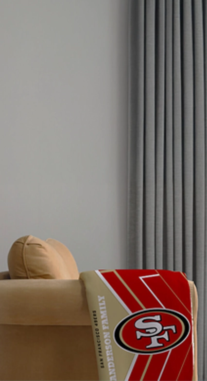 NFL Photo Blankets: A personalized San Francisco 49ers blanket with a family name, draped over a chair.