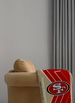 NFL Photo Blankets: A personalized San Francisco 49ers blanket with a family name, draped over a chair.