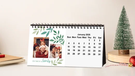 Photo desktop calendar: A spiral-bound photo desk calendar displaying the month of January 2026, with a photo collage of a family and a green leaf border design.