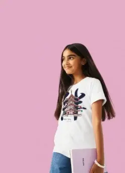 Customizable apparel: A girl in a white t-shirt and blue jeans, looking up and to the side, holding a small lavender notebook against a solid pink background.