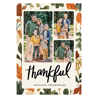 Seasonal cards & invitations: A vertical card with a watercolor autumn leaf border, displaying three family photos: a large image of parents with four young boys, a smaller image of the four boys, and a smaller image of the parents. Below the photos, the word thankful is in black script, followed by WITH LOVE, THE REYNOLDS in black text.