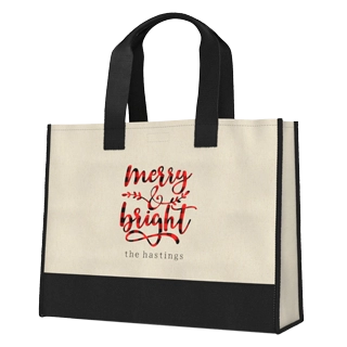 Premium Canvas Totes: A cream and black two-tone tote bag with black handles, featuring the phrase merry & bright in red plaid script with leaf accents, and the name the hastings in black text below it.